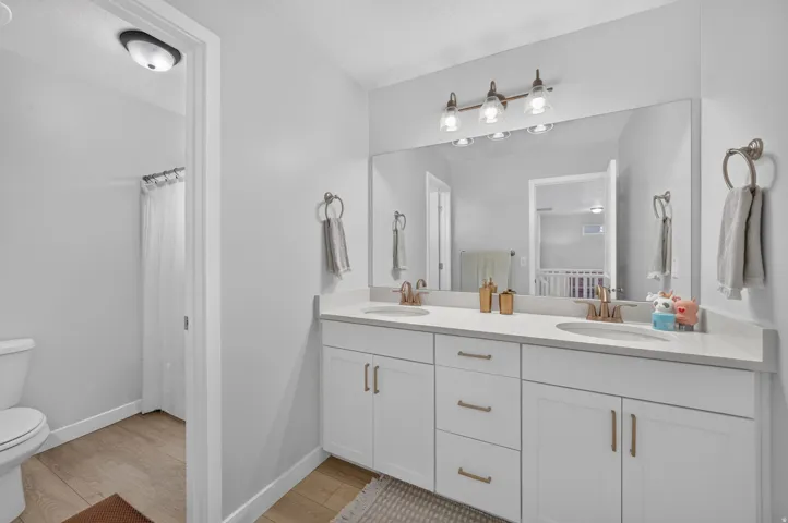 Dual vanity with undermount sinks, bronze finish faucets, and white cabinetry