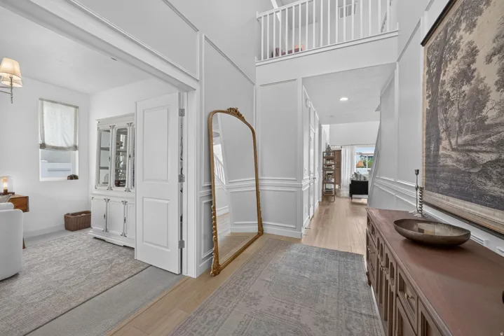 Two-story foyer featuring wood-finish flooring, wainscoting, and a white balustrade