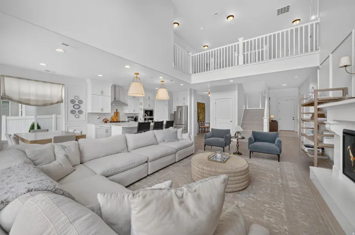 Two-story living area with high ceilings, recessed lighting, and wood-finish flooring