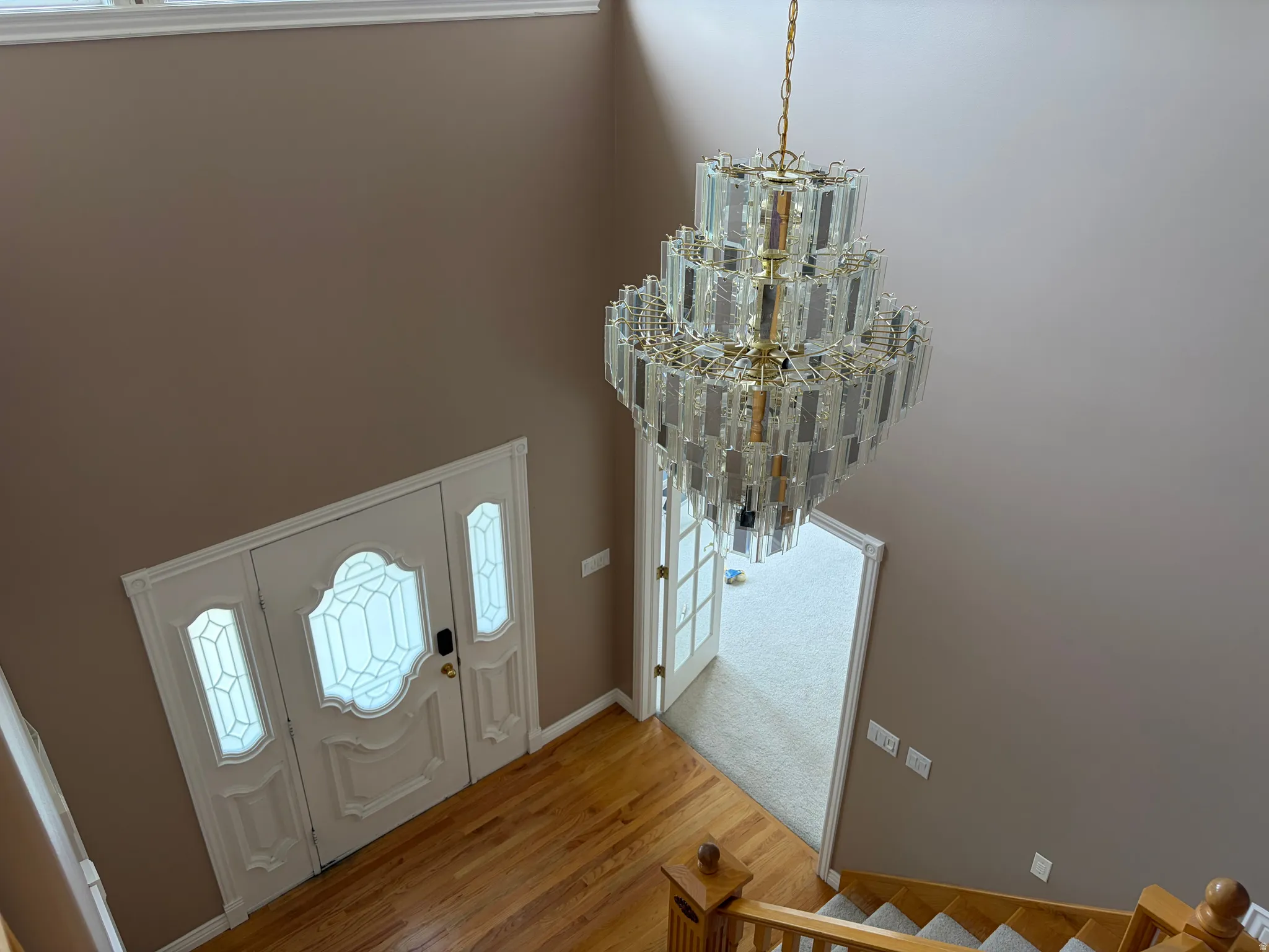 Elegant foyer showcasing soaring ceilings, a striking multi-tiered crystal chandelier with brass accents, and refined architectural detailing