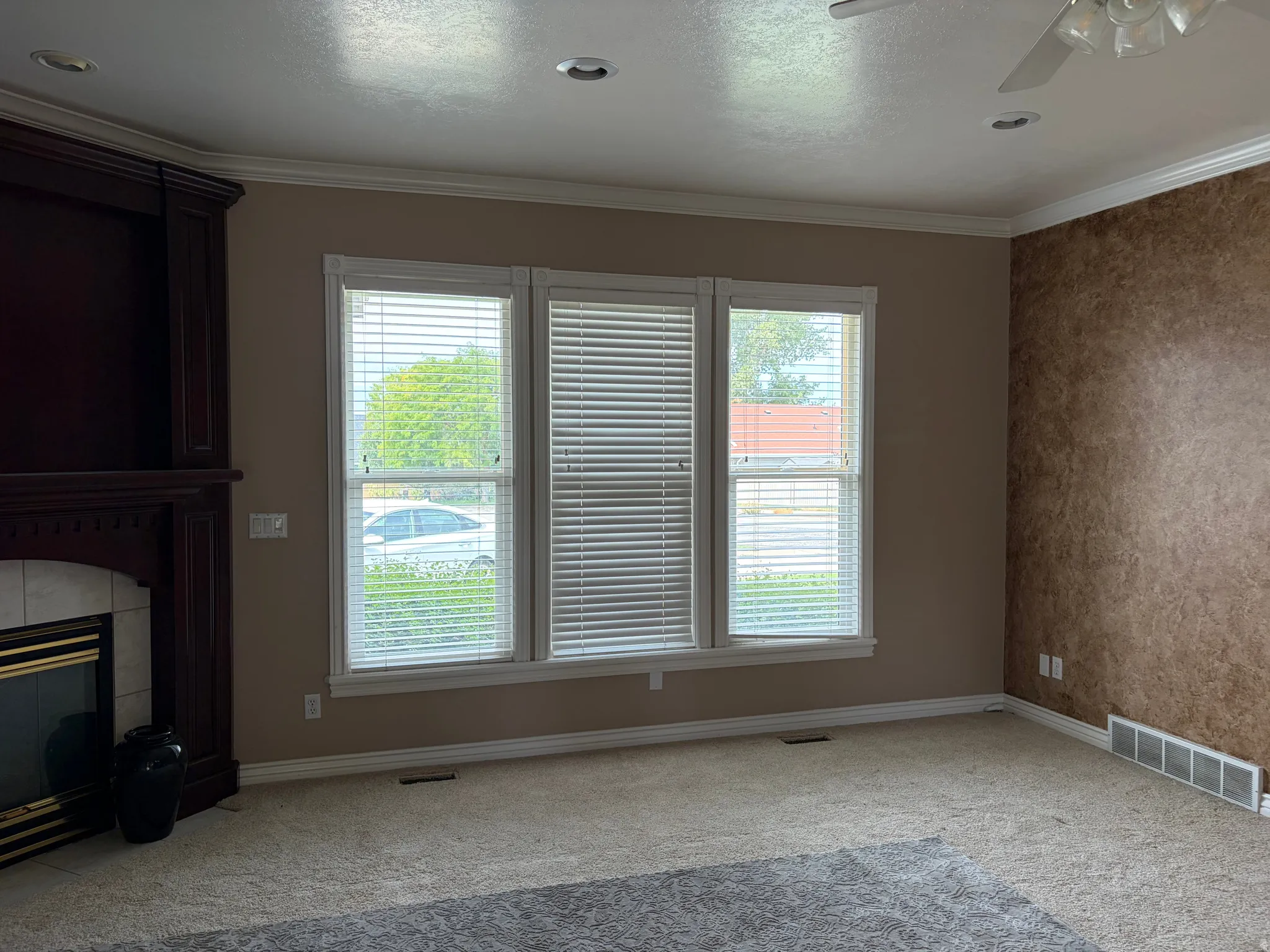 Built-in dark wood cabinetry with fireplace, white crown molding, recessed lighting, and a three-panel window