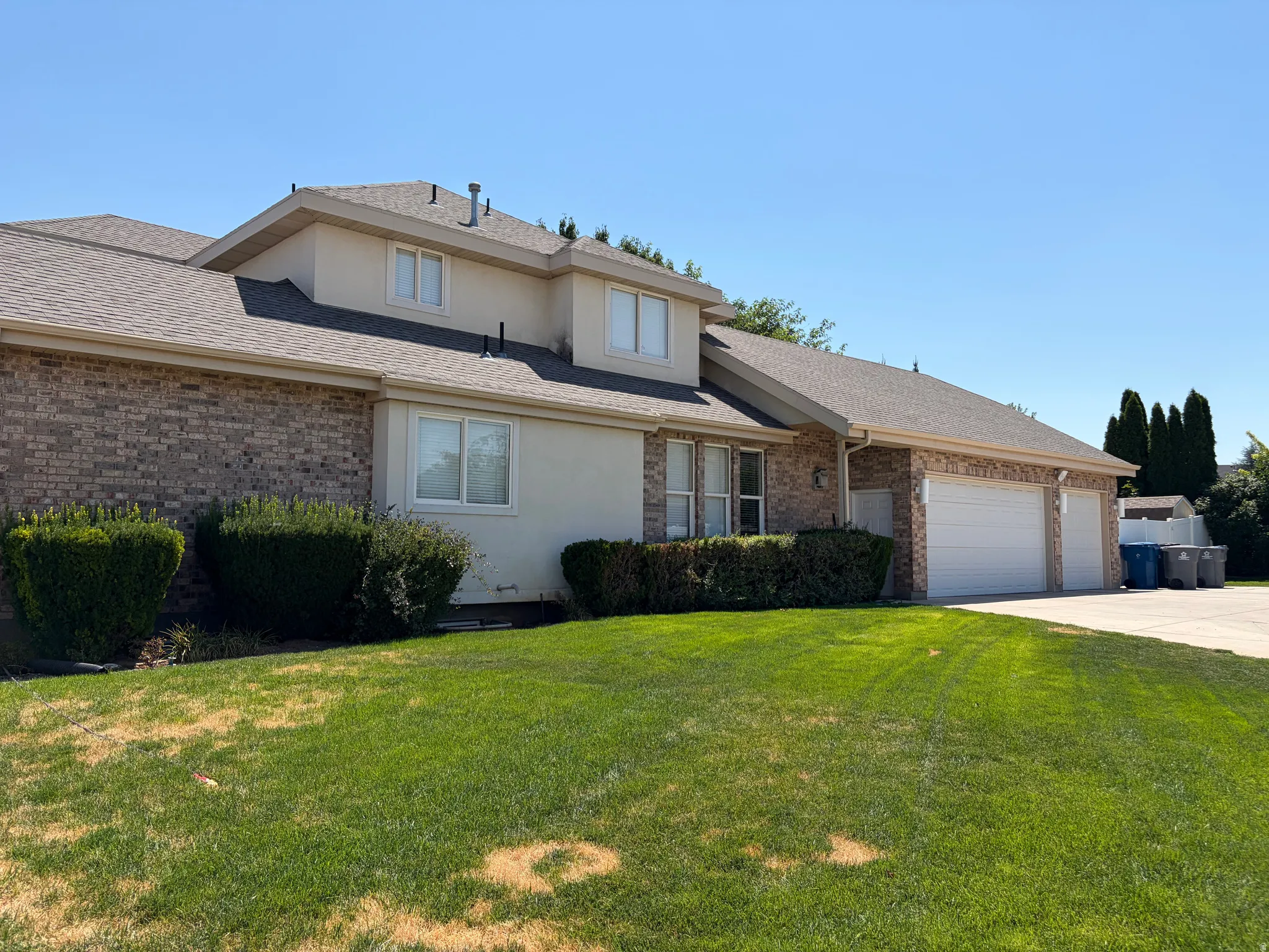 Brick and stucco exterior with multiple windows, an attached two-car garage, and a concrete driveway
