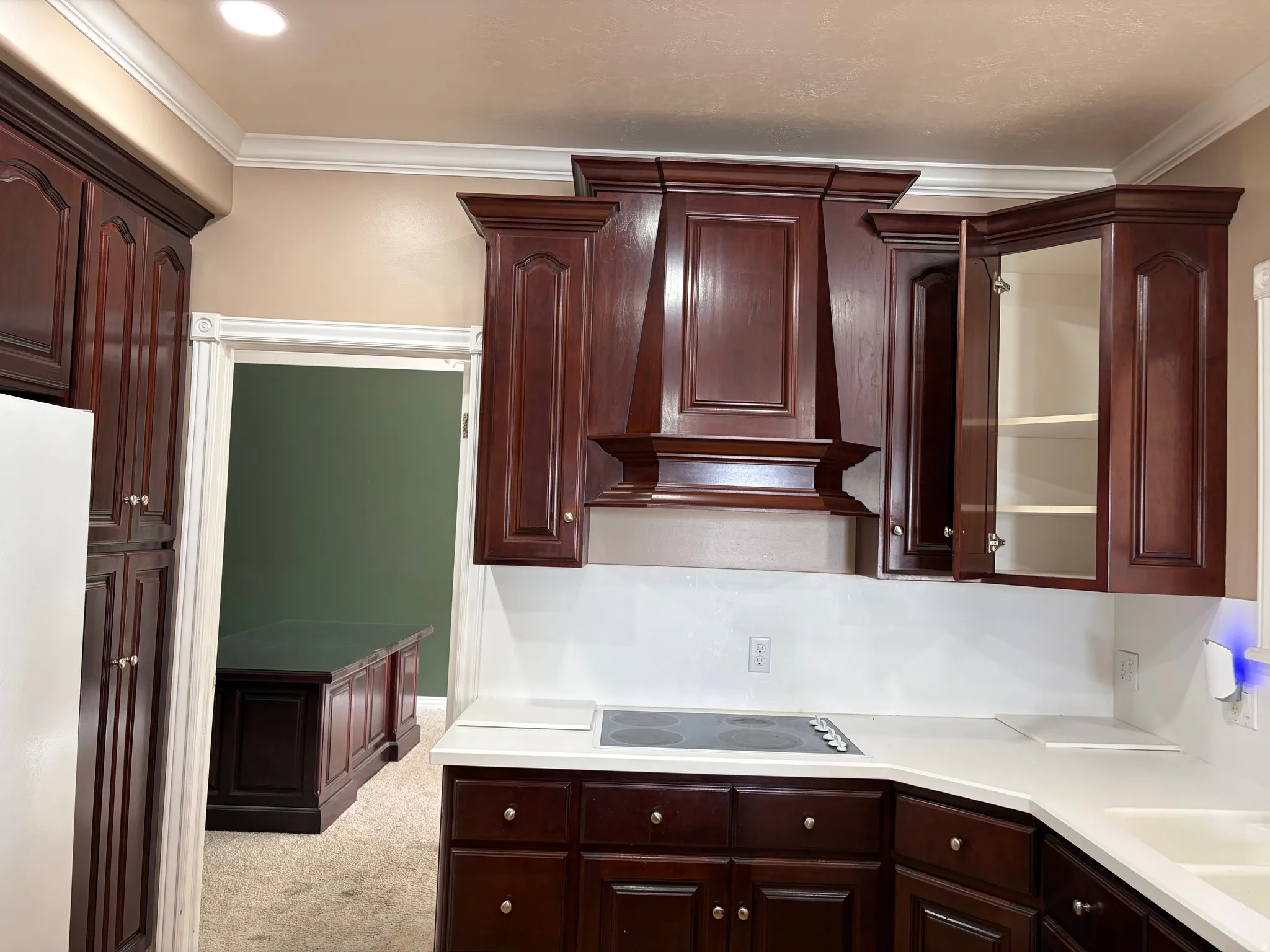 Rich wood-finish cabinetry, built-in cooktop, solid surface countertops, and crown molding