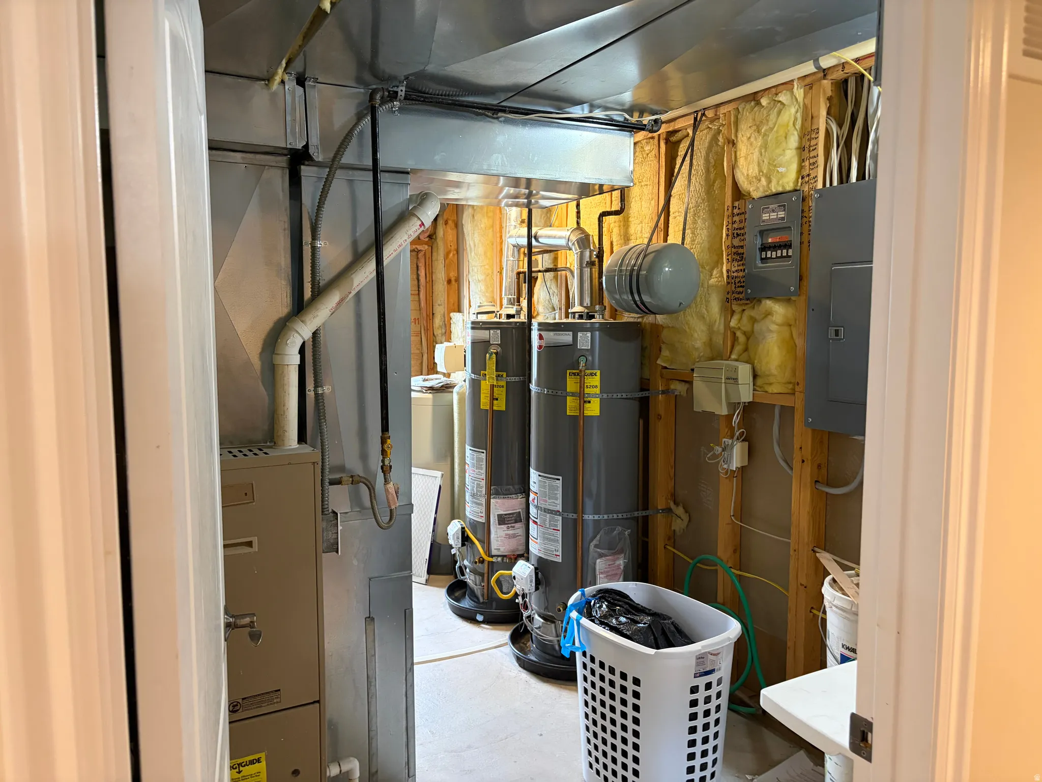 Dedicated utility space featuring multiple water heaters, exposed ductwork, a furnace, and electrical panels
