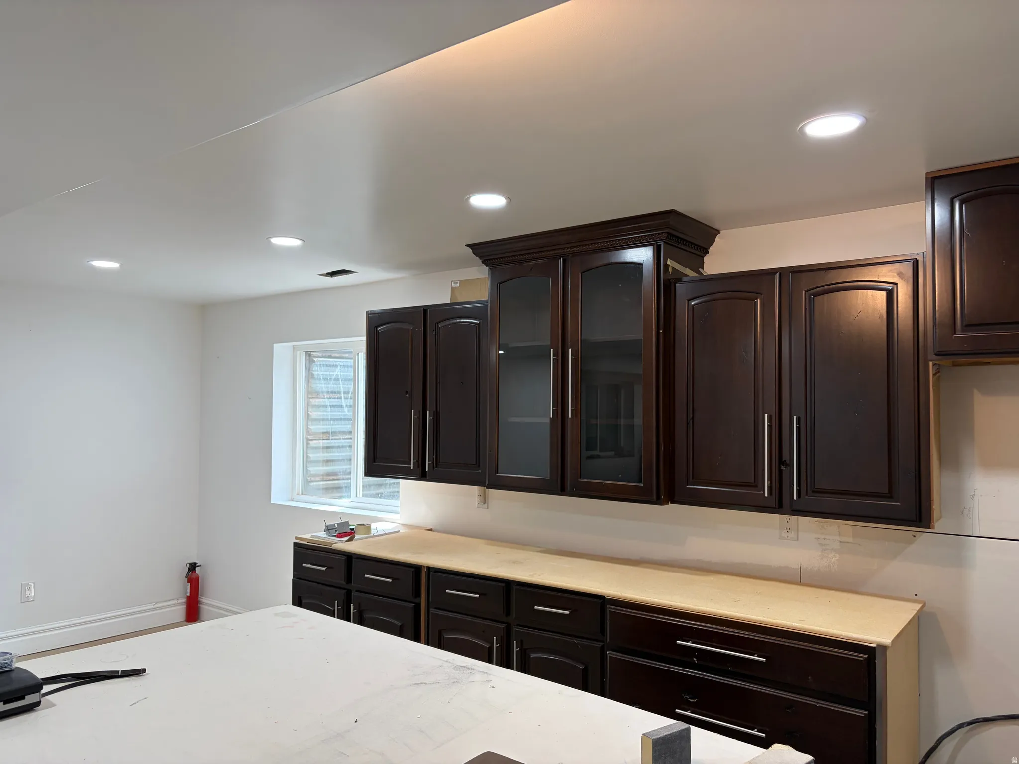 Unfinished kitchen in basement dark wood-finish cabinetry with glass-front accents