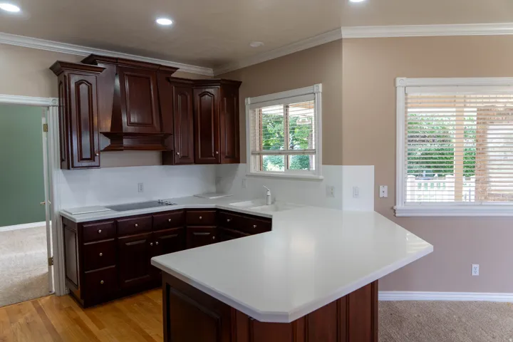 Kitchen featuring dark wood cabinetry, light countertops, built-in cooktop, and a kitchen island with seating