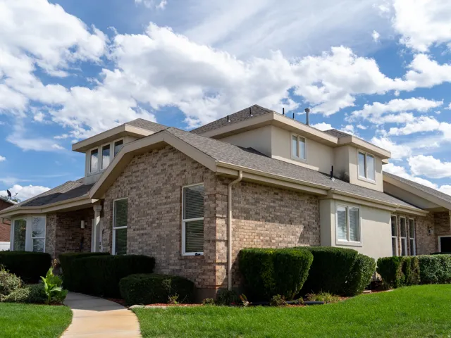 Brick and stucco exterior with multiple windows, an attached two-car garage, and a curved concrete walkway