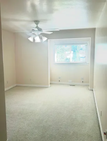 Room featuring neutral-toned carpeting, a window with blinds, a ceiling fan with integrated lighting, and light-colored wall paint