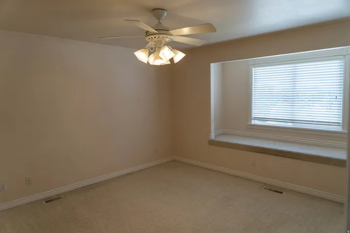 Recessed window with a built-in bench, ceiling fan with integrated lighting, and neutral carpet flooring