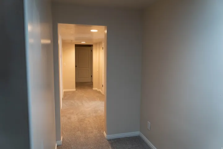 Hallway featuring recessed lighting, light-toned carpeting, and a paneled interior door