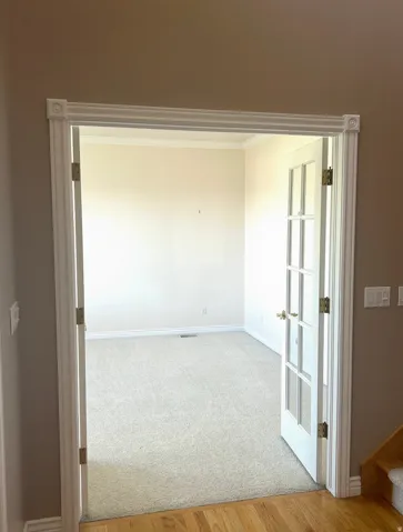 Room with light-colored carpet, crown molding, and white trim