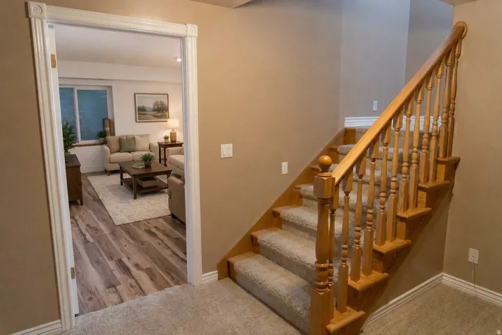 Wood-finish flooring, white trim, and a carpeted staircase with a wood handrail