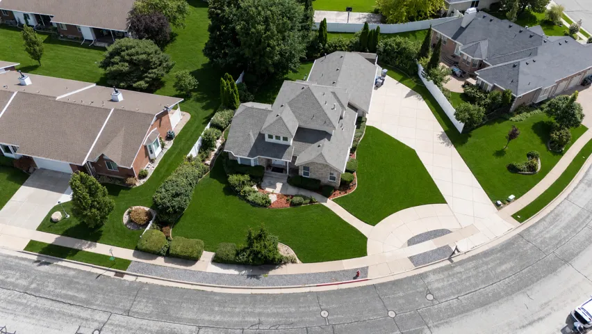 Expansive property featuring a stone exterior, multiple rooflines, a circular driveway, mature landscaping, and an attached garage