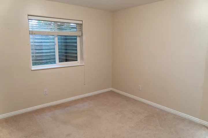 Neutral tone wall paint, light-colored carpet, and a window with blinds