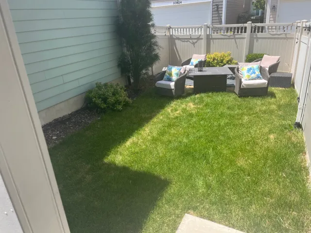 Enclosed yard featuring a manicured lawn, established landscaping, and a privacy fence