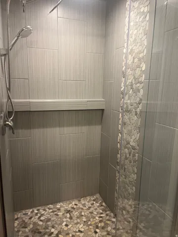 Walk-in shower with textured wall tile and a built-in bench