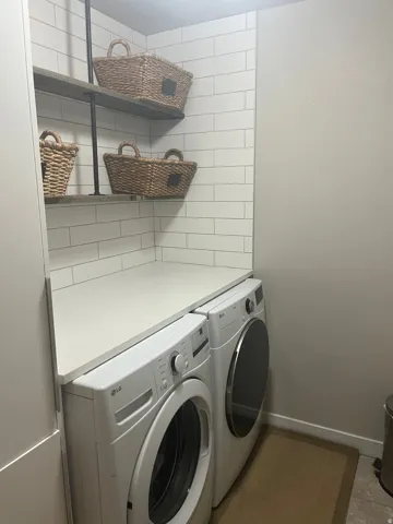 White subway tile backsplash with built-in shelving, solid surface countertop, and neutral wall color