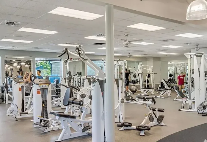 Fitness center featuring a variety of exercise equipment, mirrored walls, ceiling fans, and recessed lighting