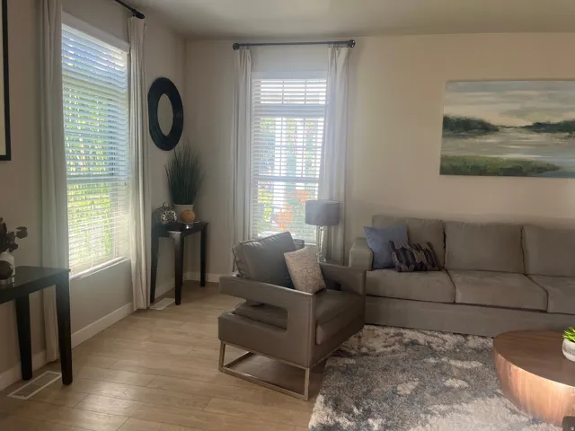 Multiple windows with blinds, light-toned walls, and wood-finish flooring