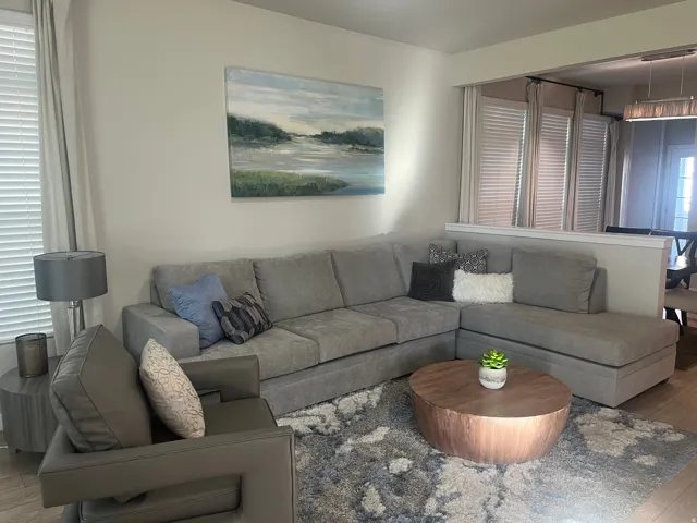 Interior with light-toned walls, a window with horizontal blinds, wood-finish flooring, and a half-wall partition