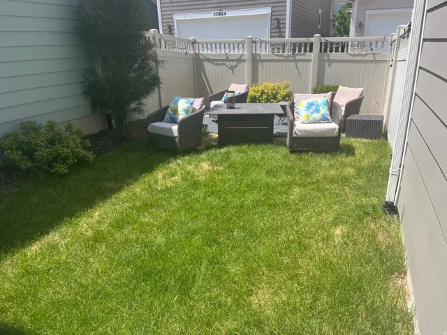 Enclosed backyard space featuring a lawn, privacy fencing, and established greenery