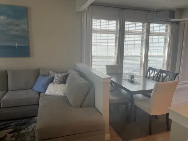 Dining area featuring a dark wood-finish table and seating, accompanied by large windows with blinds