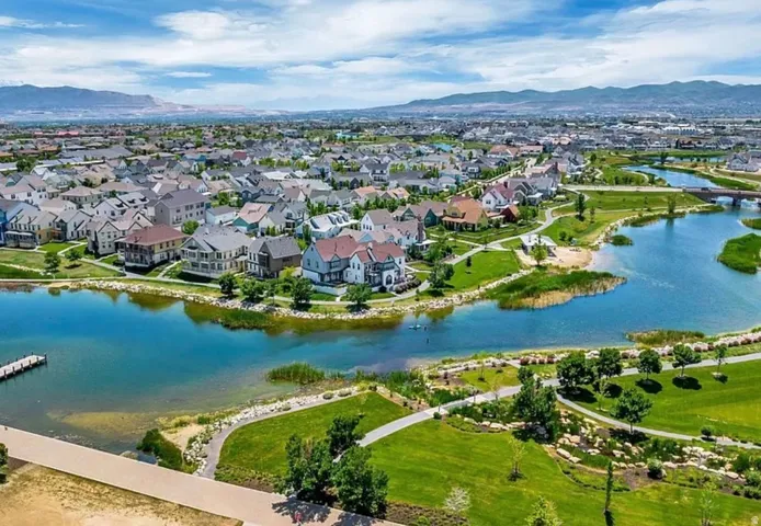Expansive residential community with waterfront properties, featuring a large body of water, green spaces, and a mountainous backdrop