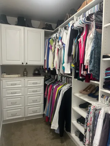 Custom closet system featuring white shaker-style cabinetry, multiple hanging rods, built-in shelving, and drawers with brushed nickel hardware