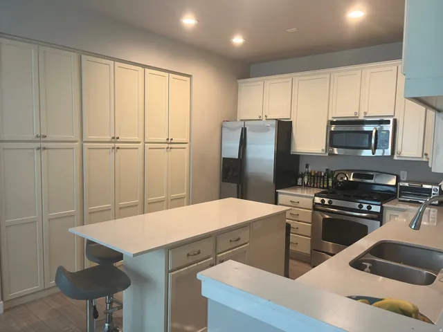 Modern kitchen featuring extensive cabinetry, stainless steel appliances, a center island with countertop seating, and recessed lighting