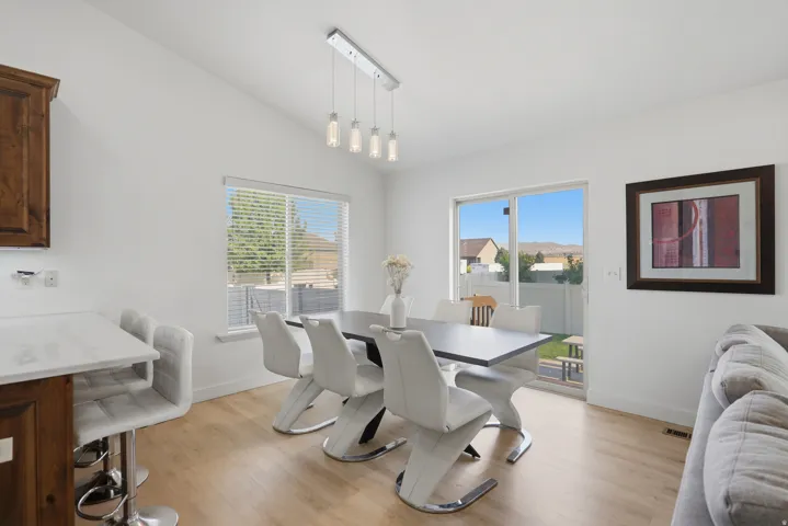Dining area featuring wood-finish flooring, a contemporary linear chandelier, and a sliding glass door