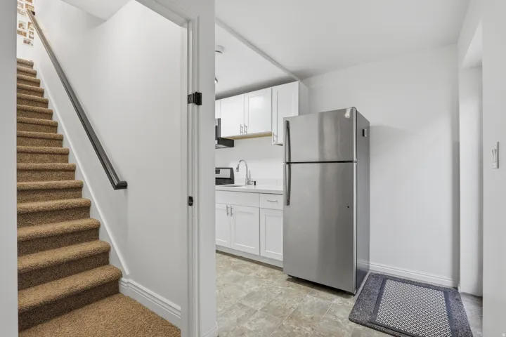 Carpeted staircase with dark handrail and white risers