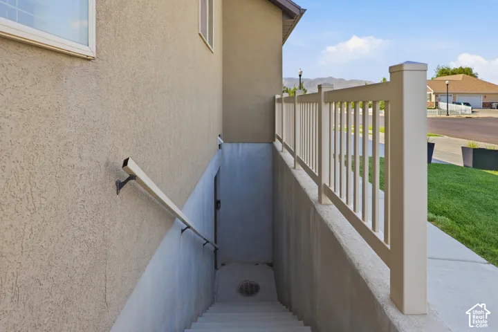 Stucco exterior wall with two windows, concrete stairs, and a metal handrail