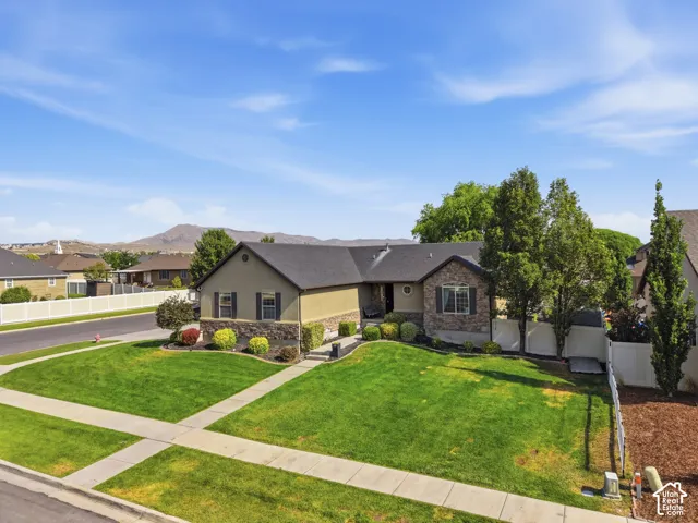 Stucco exterior with stone accenting, dark shingle roofing, and established landscaping