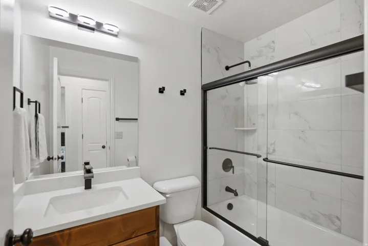 Modern vanity with wood-finish cabinetry, white countertop, and matte black fixtures