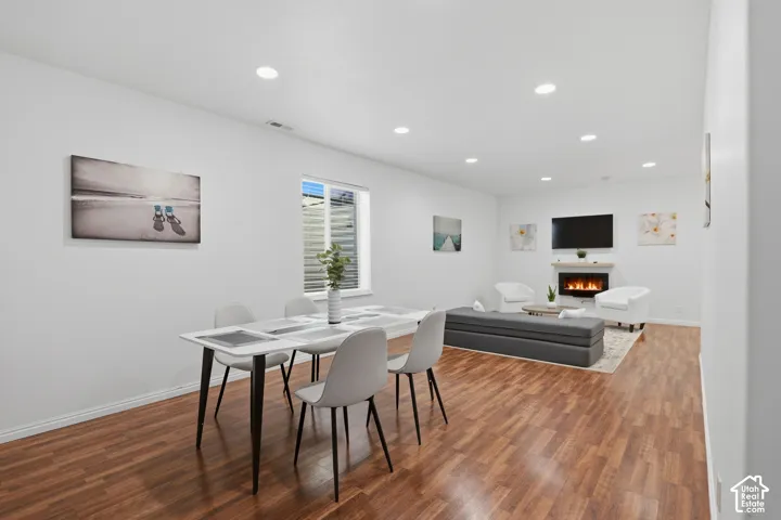 Open-concept living space featuring wood-finish flooring, recessed lighting, and a built-in fireplace with a mantel
