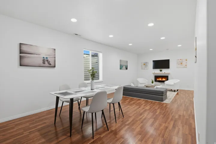 Open-concept living space featuring wood-finish flooring, recessed lighting, and a built-in fireplace with a mantel