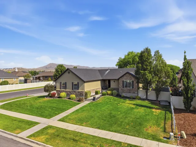 Stucco exterior with stone accenting, dark shingle roofing, and established landscaping