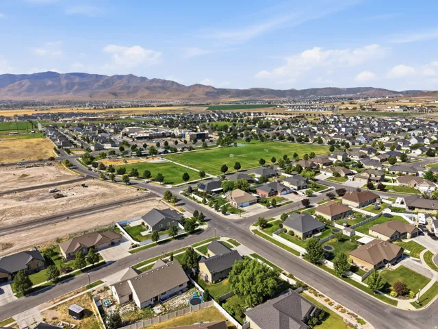 Expansive residential neighborhood with distant mountain terrain, featuring a substantial green space, manicured streets, and mature trees