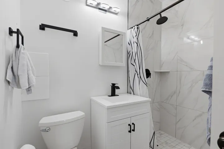 White vanity with black hardware, black faucet, and white countertop