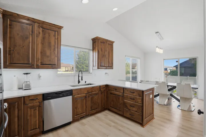 Vaulted ceilings, wood-finish flooring, dark wood cabinetry, white countertops, and sliding glass doors