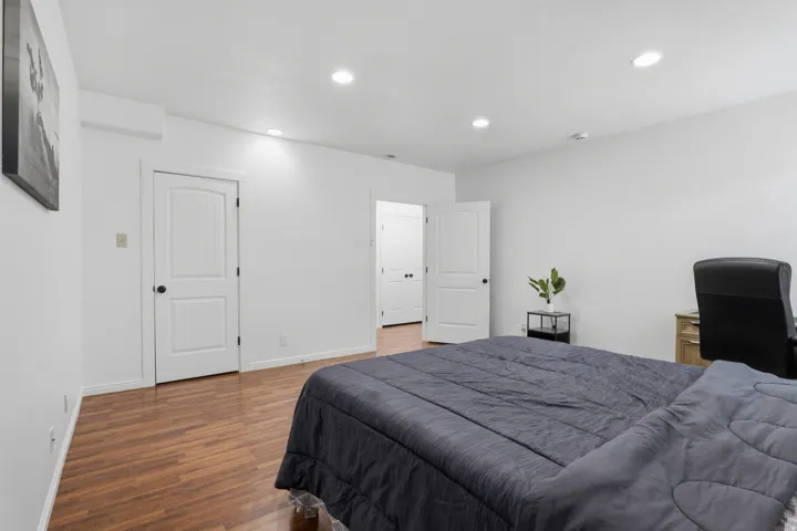 Wood-finish flooring throughout, bright white walls, recessed lighting, and white paneled doors with black hardware