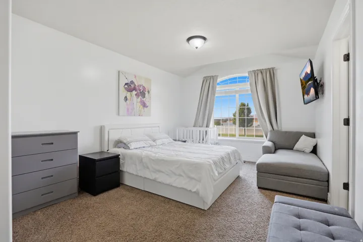 Spacious room with an arched window, white walls, and carpet flooring