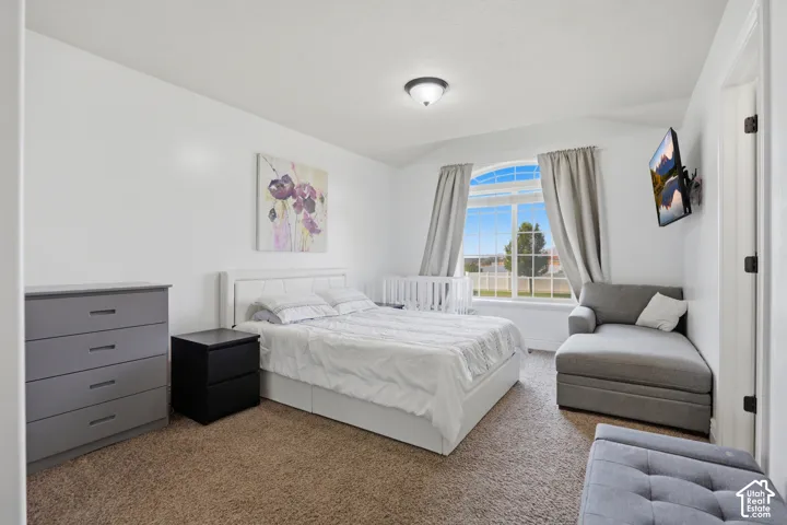 Spacious room with an arched window, white walls, and carpet flooring
