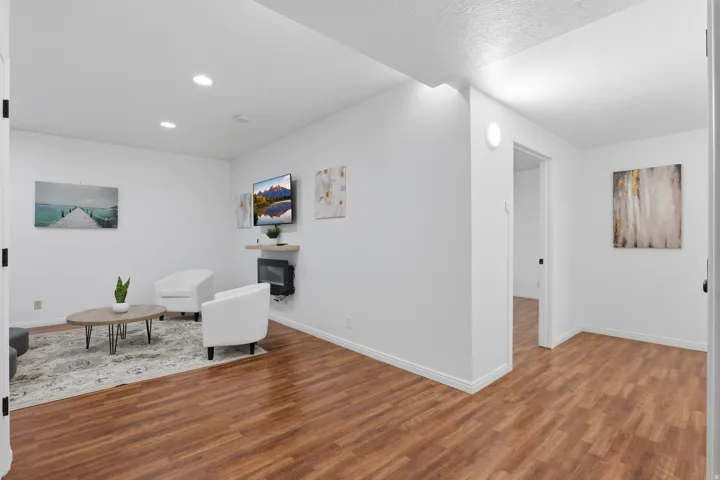 Recessed lighting, wood-finish flooring, white walls, and a wall-mounted fireplace