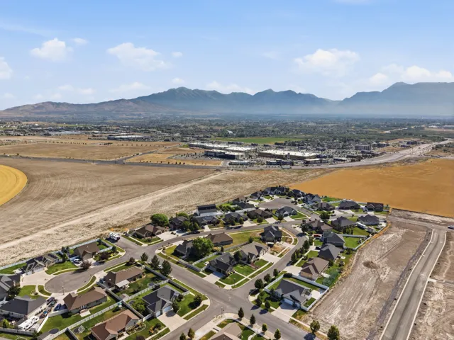 Established residential development with manicured lawns and mature trees, surrounded by open fields and distant mountains