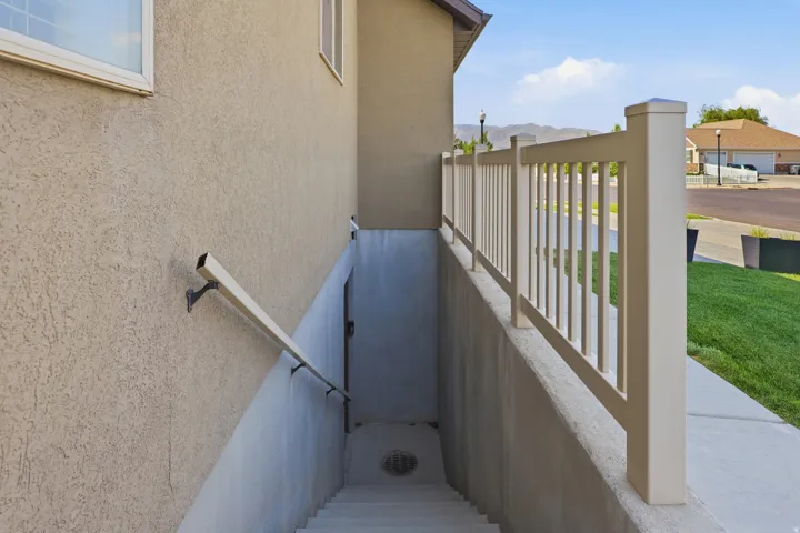 Stucco exterior wall with two windows, concrete stairs, and a metal handrail