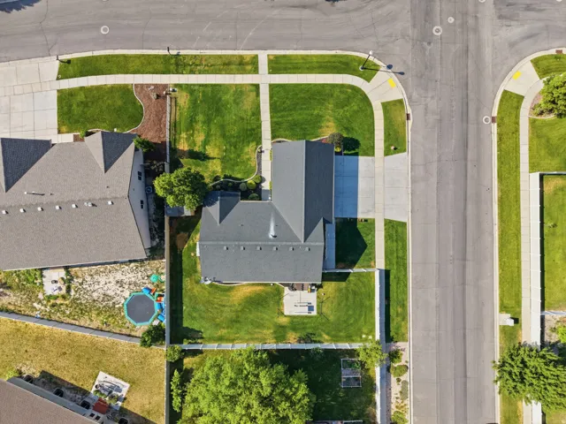 Pitched roof residence featuring a concrete driveway, front yard with green lawn, and a fenced backyard with green lawn