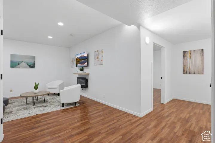 Recessed lighting, wood-finish flooring, white walls, and a wall-mounted fireplace