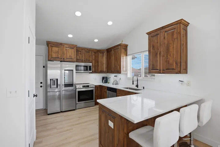 Kitchen featuring wood cabinetry, stainless steel appliances, white countertops, and wood-finish flooring