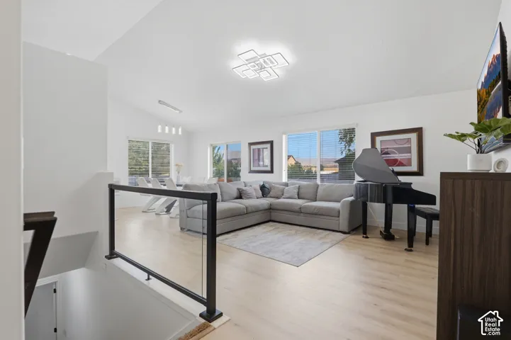Vaulted ceilings with a contemporary light fixture, light wood-finish flooring, and expansive windows
